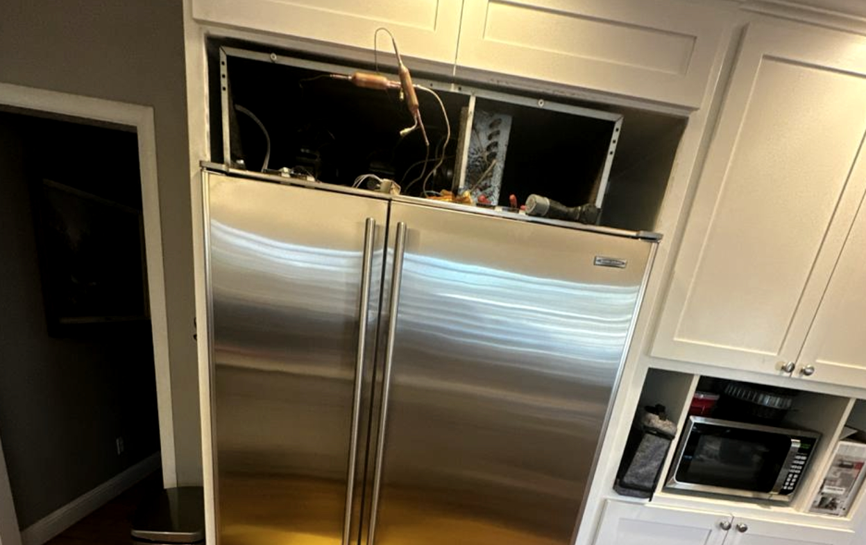 Sub-Zero built-in refrigerator compressor replacement — top service compartment open, manifold gauges connected in Houston, TX